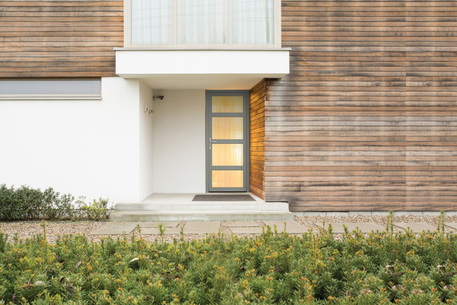 Porte d'entrée bois LONGITUDE 3 - Visuel d'ambiance Maison moderne vue de l'extérieur avec porte d'entrée grise et parties vitrées